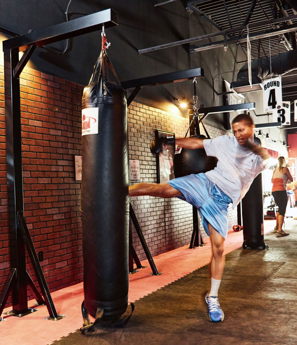 Man kicking body bag/9 Round Fitness/brick wall/lifestyle photography