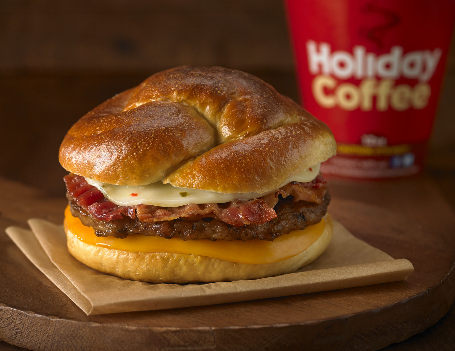 Bacon, sausage, egg, cheese breakfast sandwich/pretzel bun/coffee/food photo