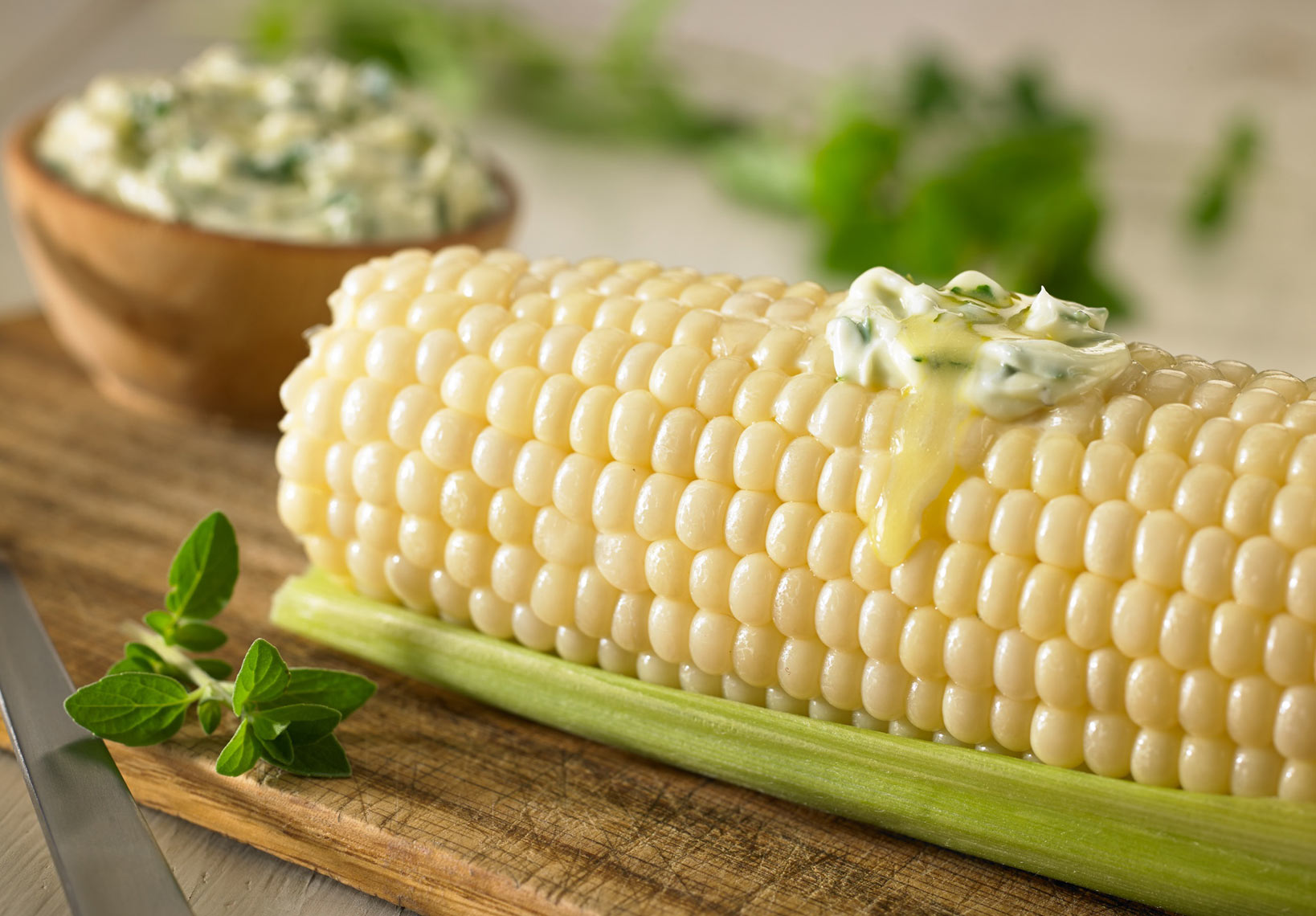 Corn on the cob/herbed butter melting on top/ramekin of herbed butter/food photography, InsideOut Studios