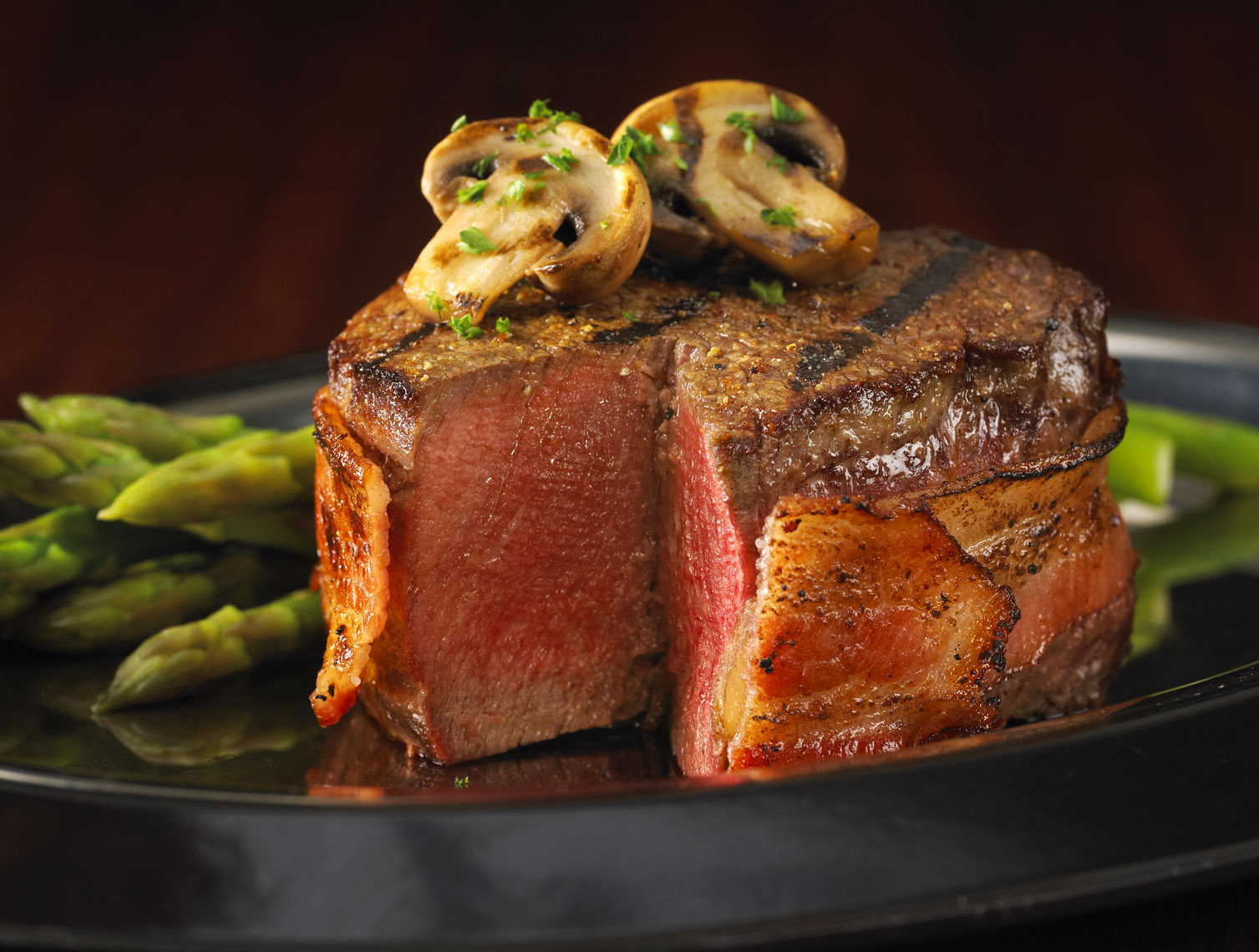 Bacon wrapped steak/slice missing/mushrooms/asparagus on the side/food photography, InsideOut Studios