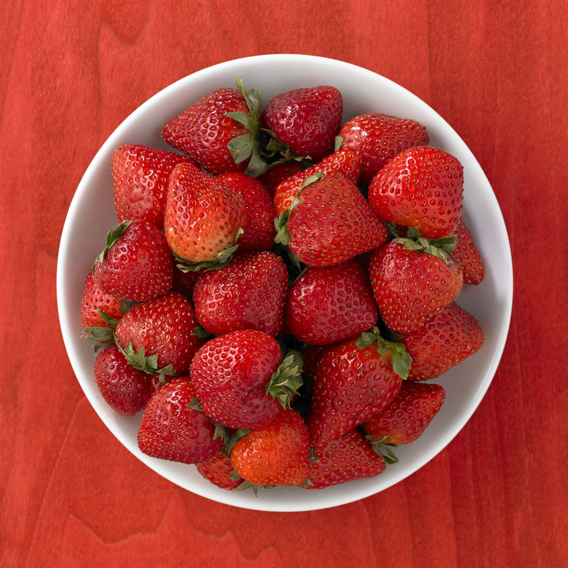 Strawberries/white bowl/top down/red wood background/food photo