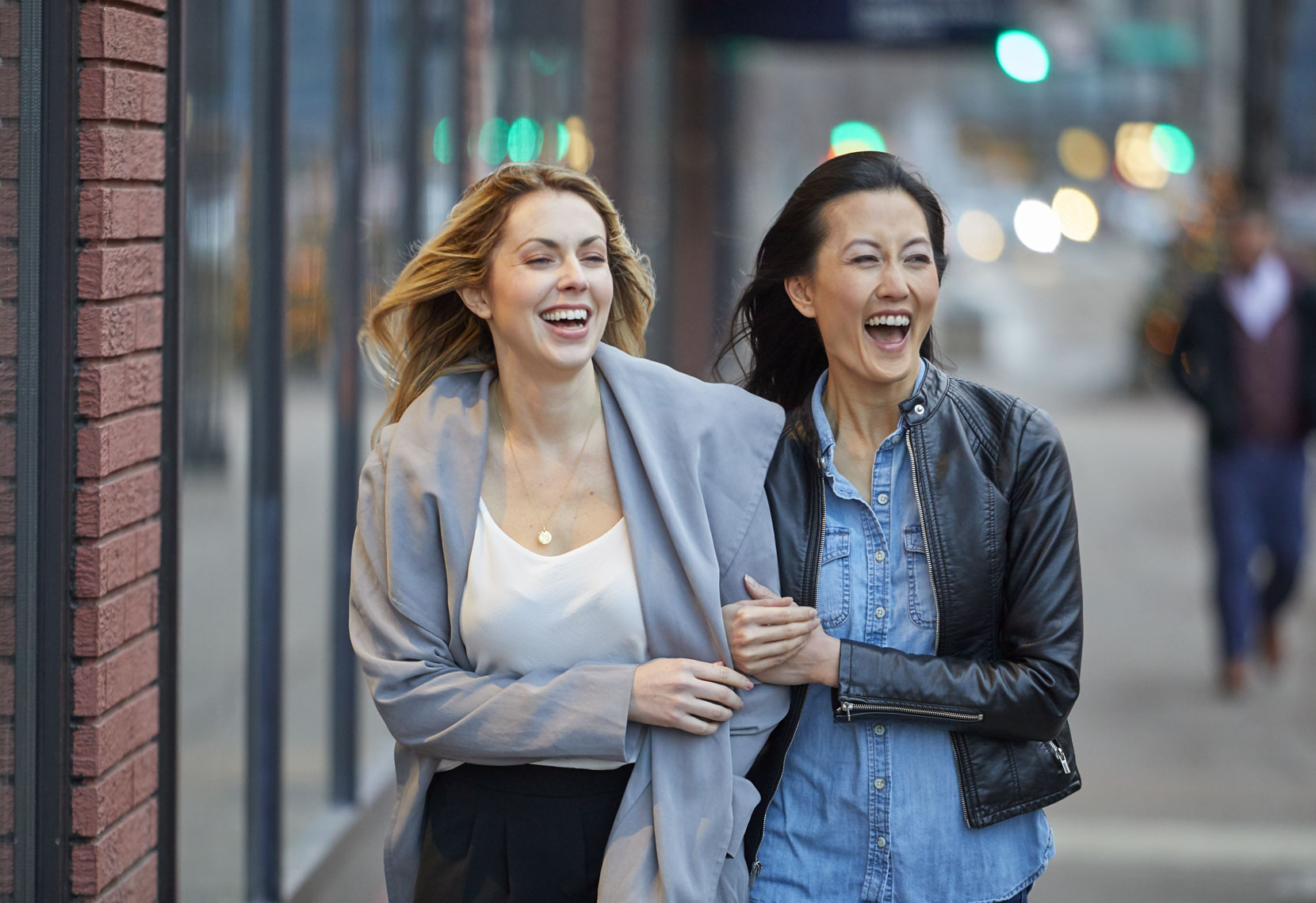 Two women walking/city sidewalk/laughing/lifestyle photography