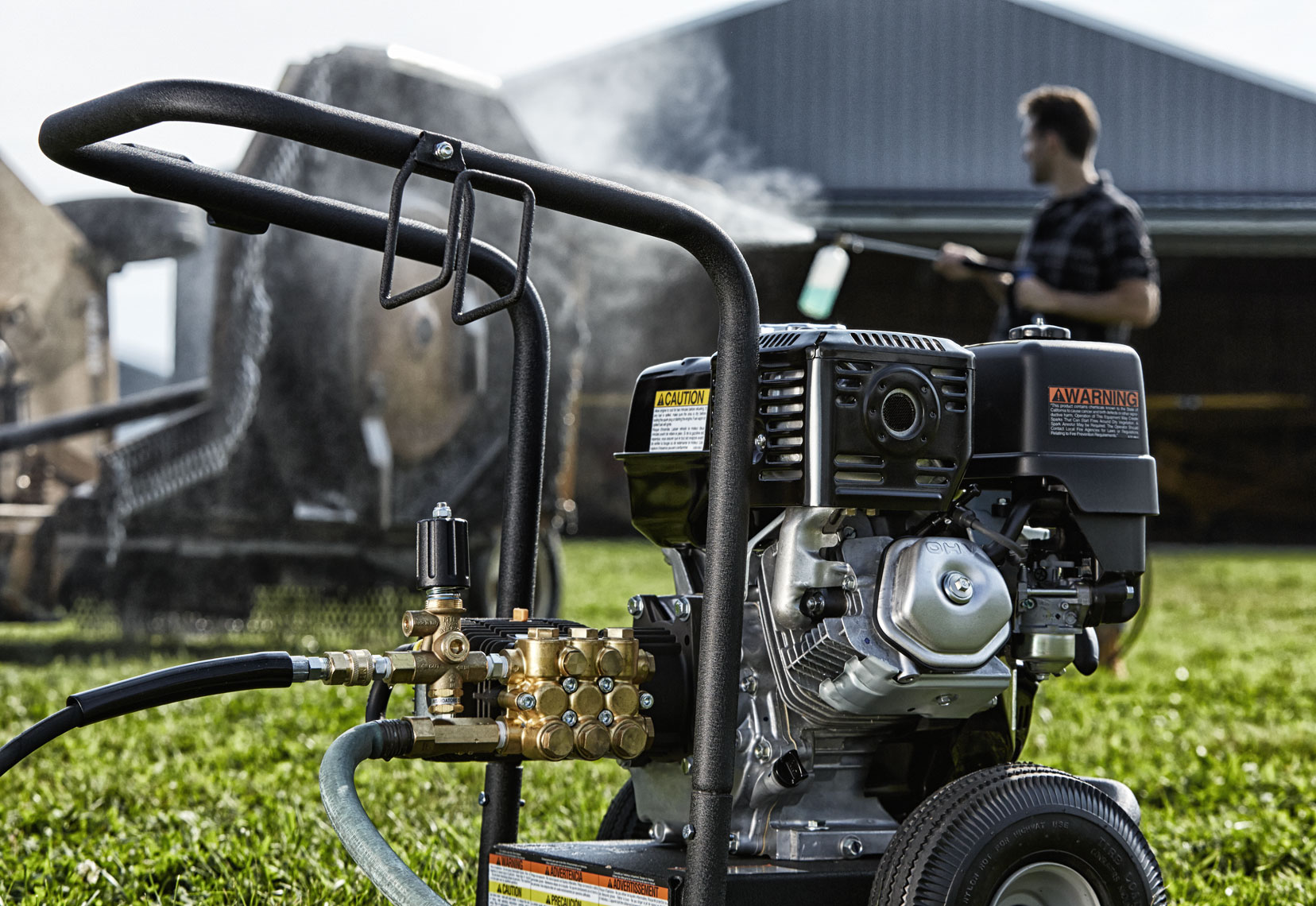 powerwasher/man washing bottom of lg. mower/location photography