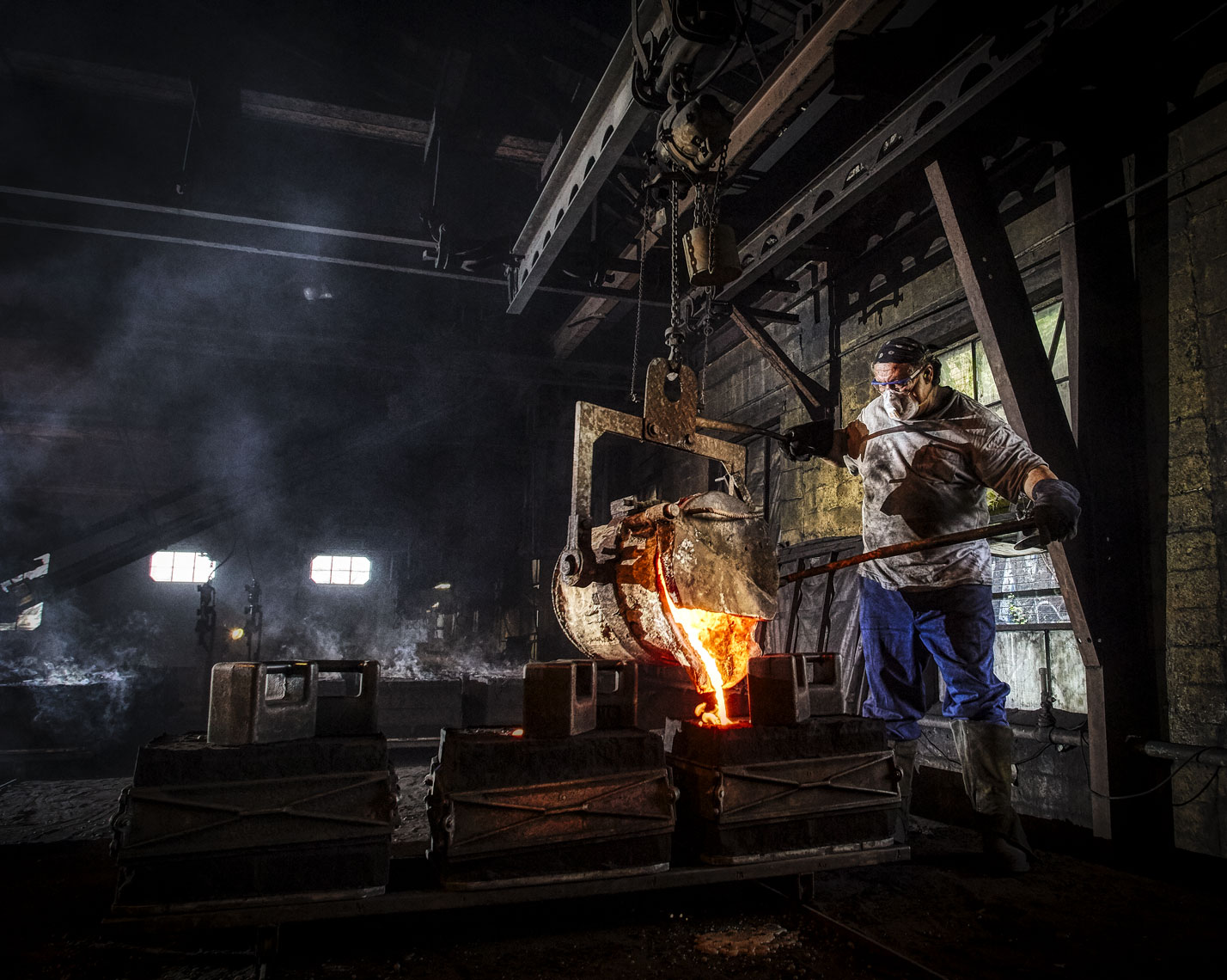 Foundry/liquid metal/worker pouring mold/industrial location photography