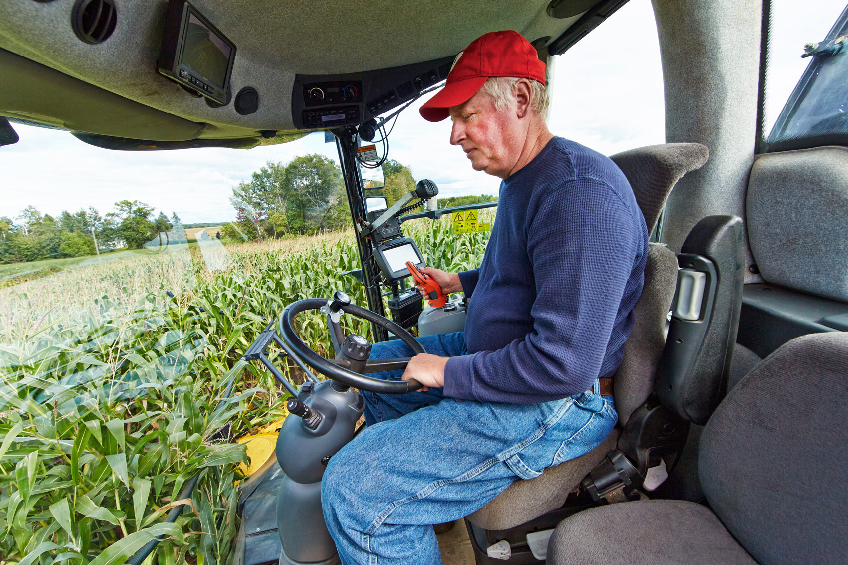 Farmer/inside tractor cab/corn field background/agriculture photography